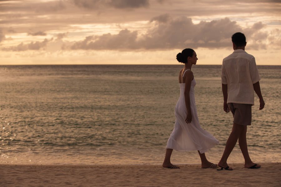 写真:黄昏時の浜辺を歩く男女